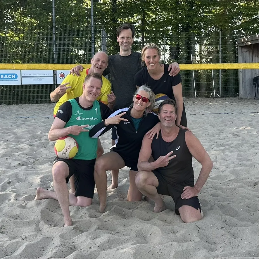 Spelers voor de sponsorborden langs het beachveld